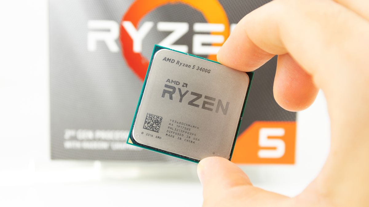 Closeup of an AMD Ryzen 5 3400G CPU held between a person's fingers.