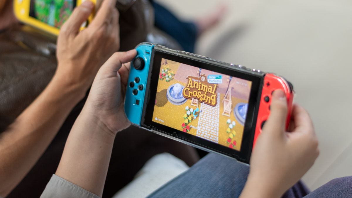 A persons hands holding a Nintendo Switch with Animal Crossing visible onscreen.