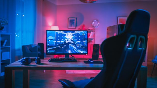 A PC gaming setup with monitor, gaming chair, and LED lighting.