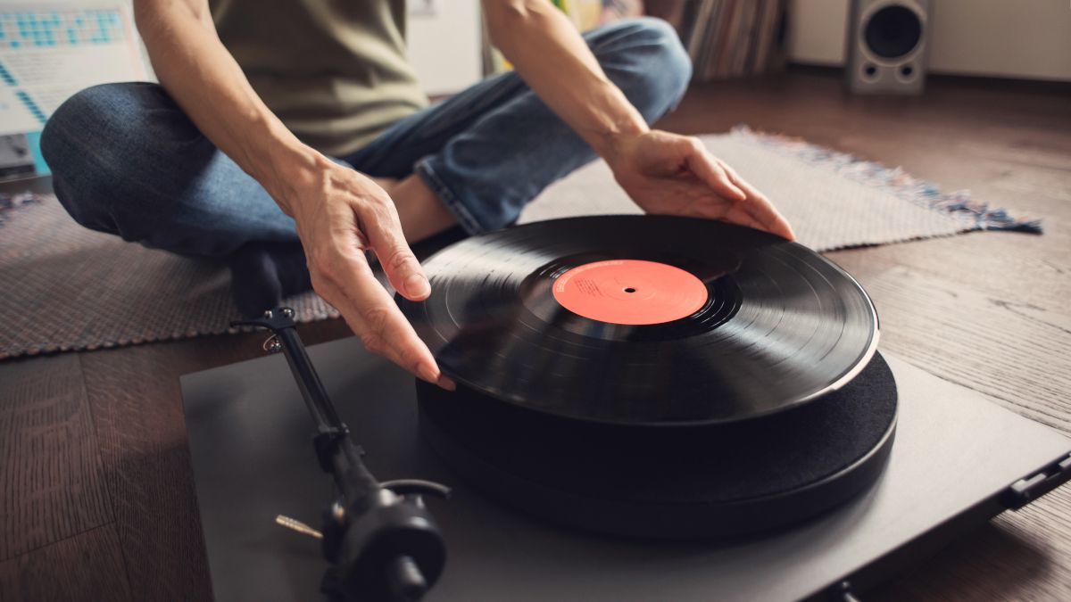 Woman's hands putting a vinyl record on a record player.