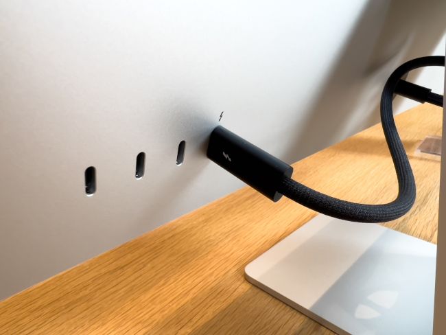 Thunderbolt cable plugged into the back of an Apple Studio Display monitor.