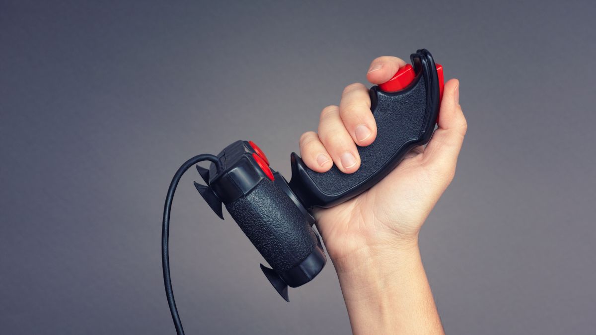 Person's hand holding up a retro joystick controller.