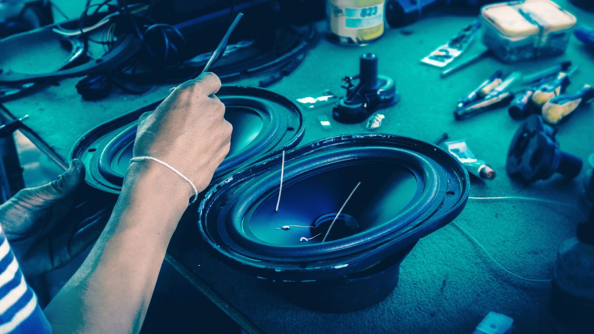 A pair of speakers being repaired on a workbench under blue light.
