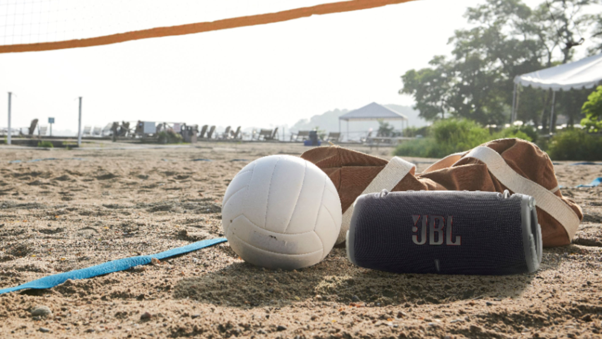 JBL XTREME3 Portable Bluetooth Speaker sitting on the sand under a volleyball net