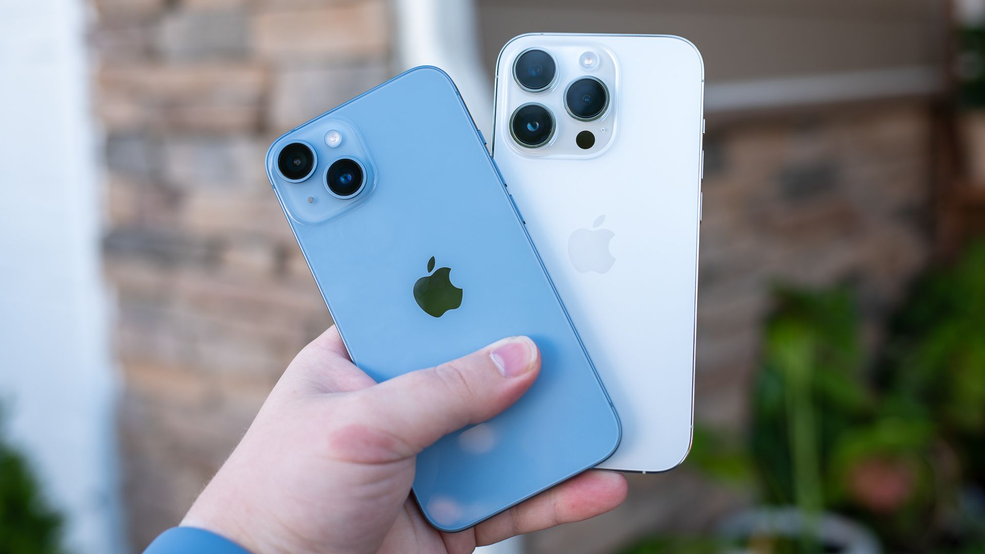 Person holding the iPhone 14 next to the iPhone 14 Pro