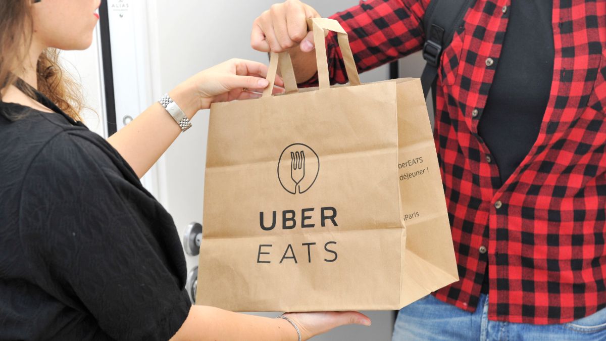Woman delivering an Uber Eats order to a man