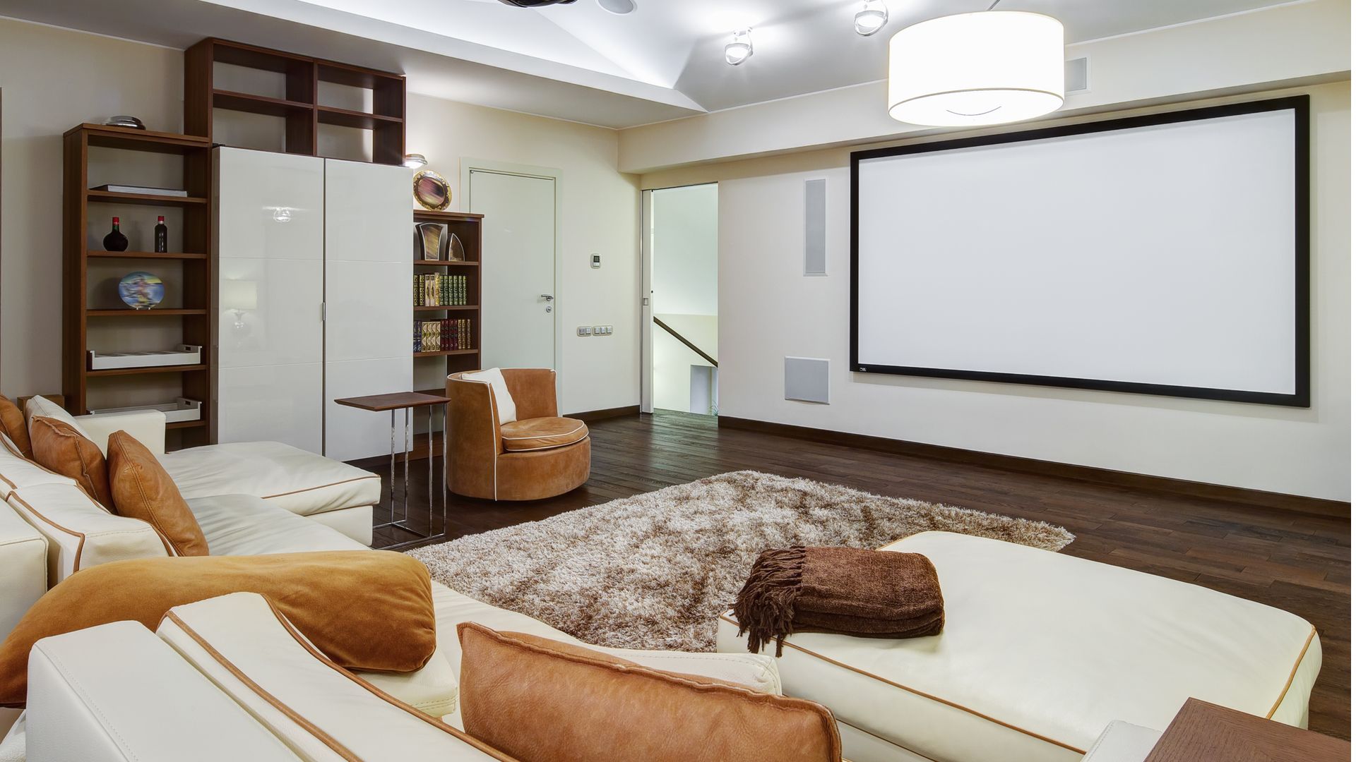 Theater room in luxury home with white big leather sofa and chairs.