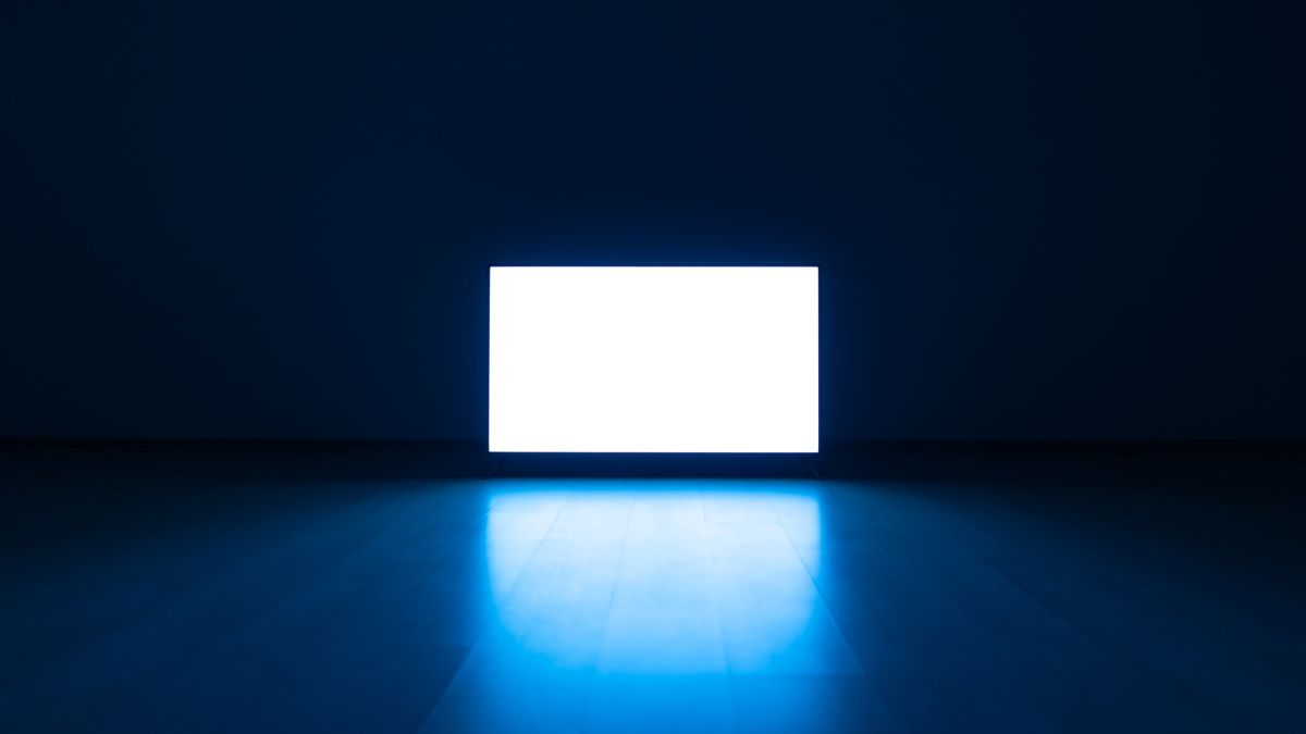 Television on the floor in a dark room with blue light reflected on the floor.