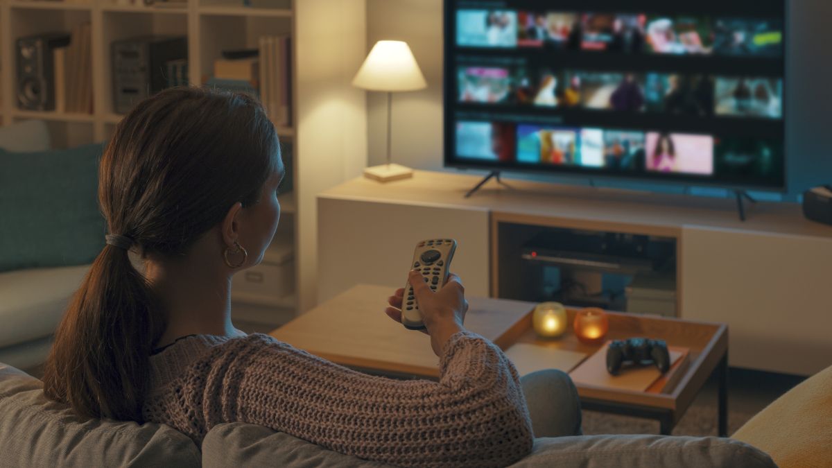 Over-the-shoulder view of a woman navigating a streaming app on a TV.