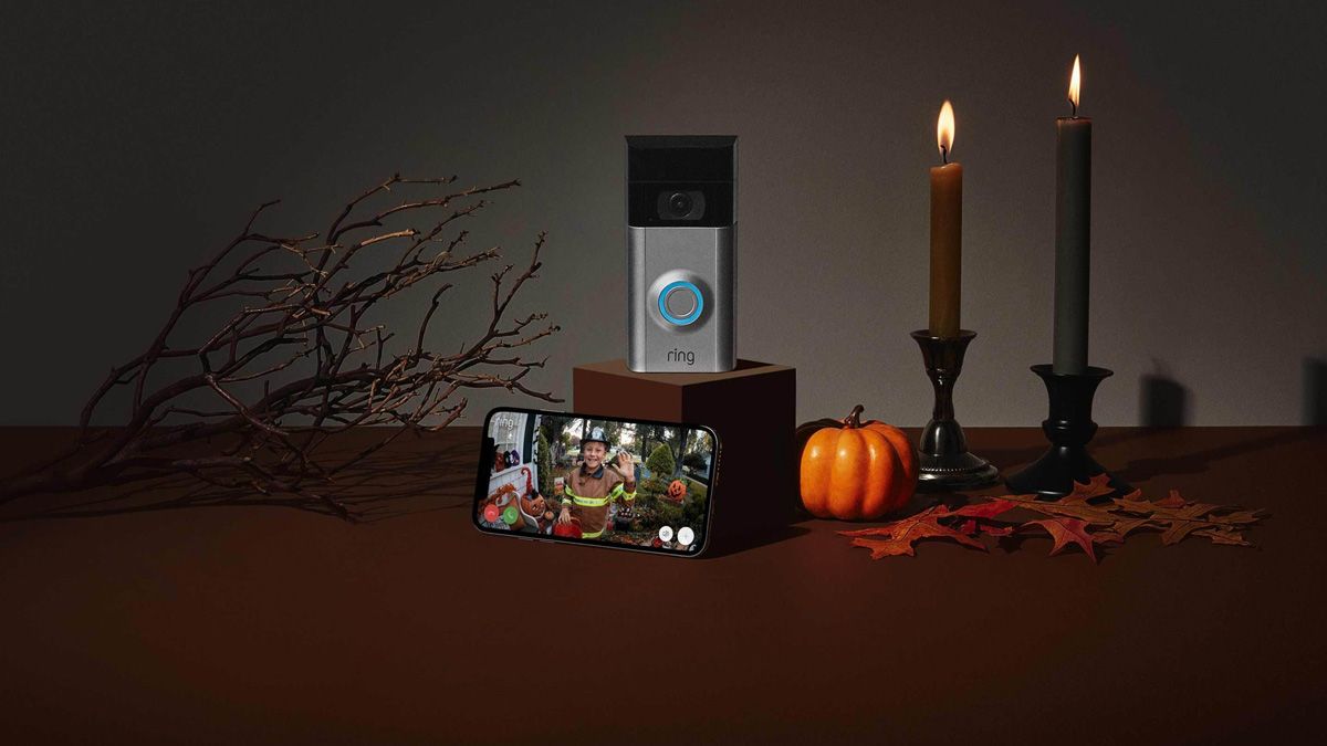 A ring doorbell and smartphone, surrounded by Halloween decor.