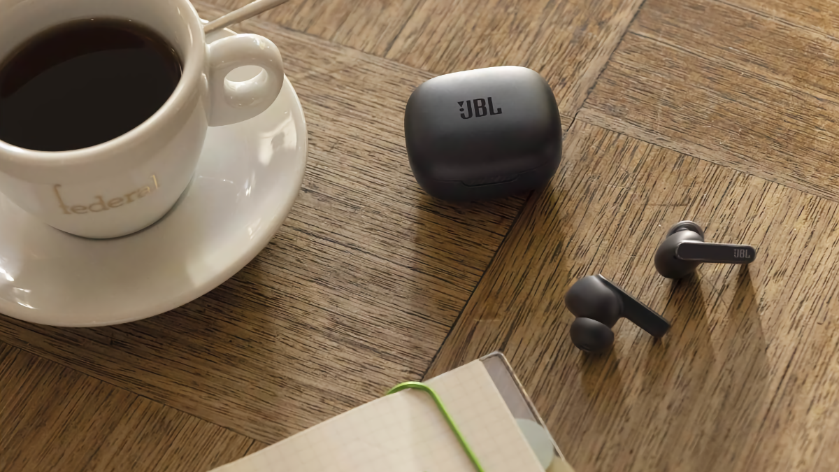 JBL Live Pro 2 Earbuds laying on a table beside a cup of coffee and a notebook