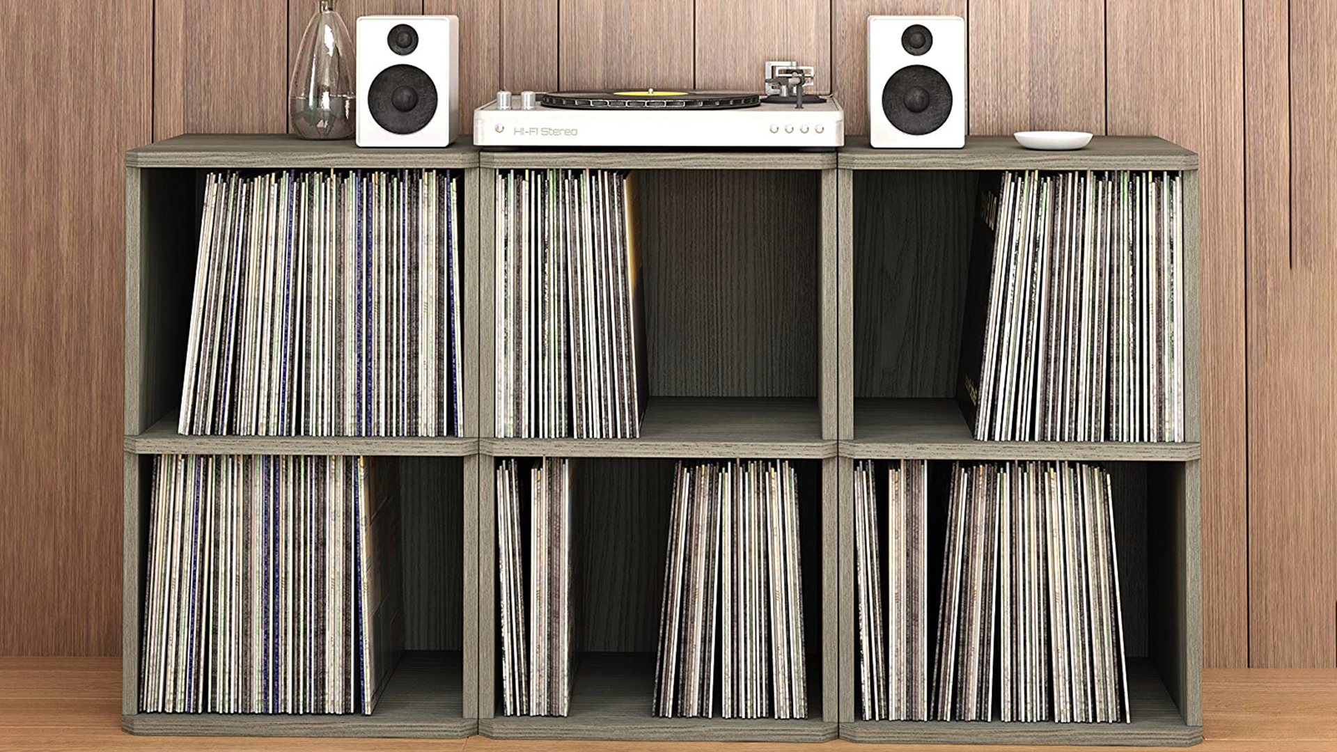 A two-shelf vinyl record storage organizer with a record player and monitors on top.