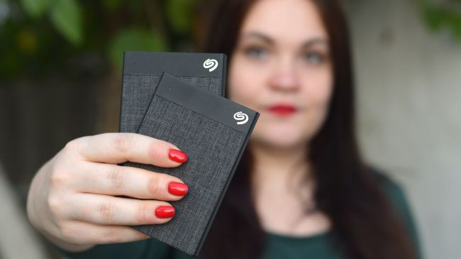 Woman holding two Seagate external hard drives.