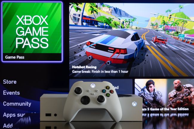 Xbox Series S in front of a screen showing Xbox Game Pass menu.
