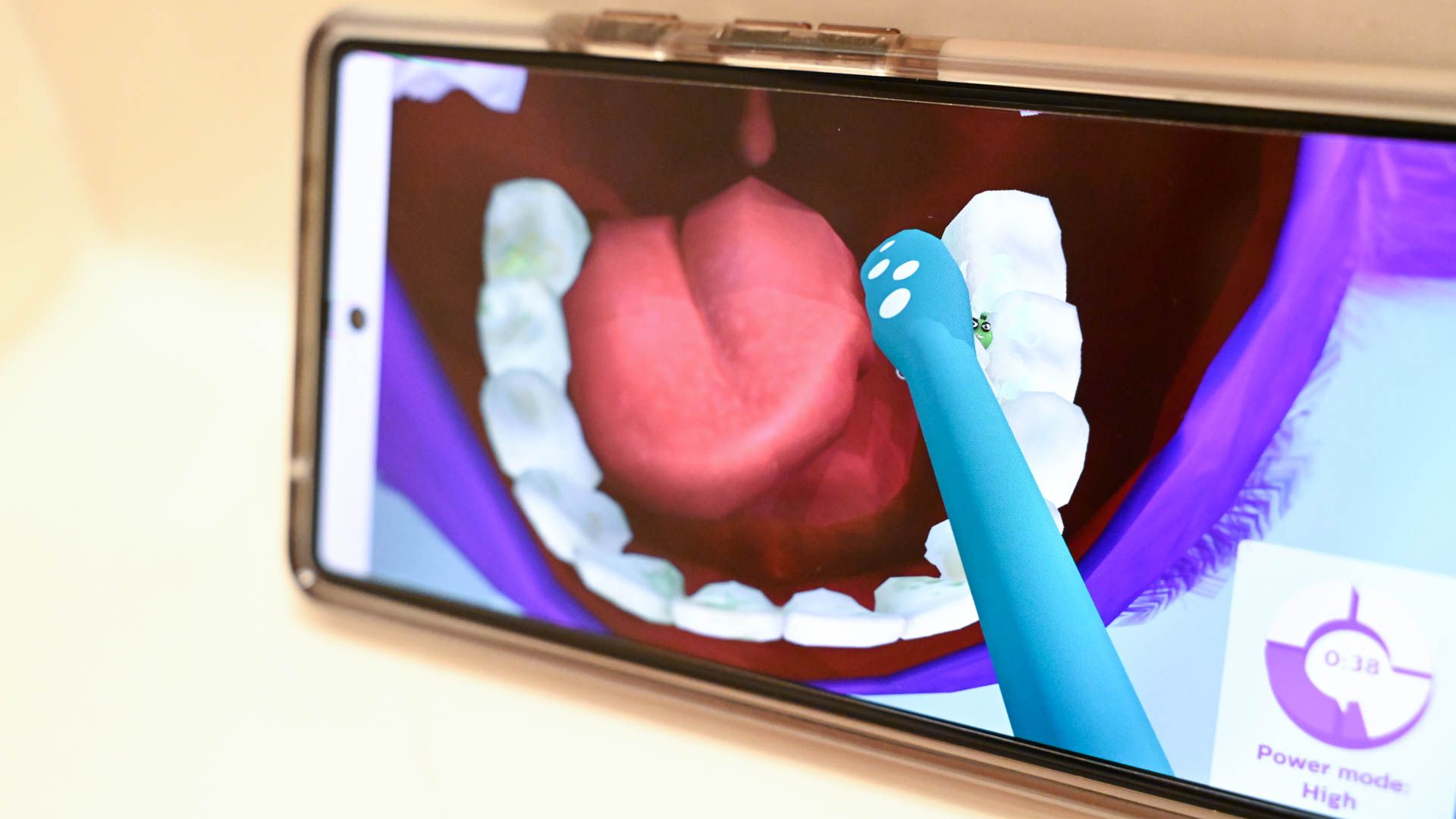 A toothbrush held up to an app showing a mouth open