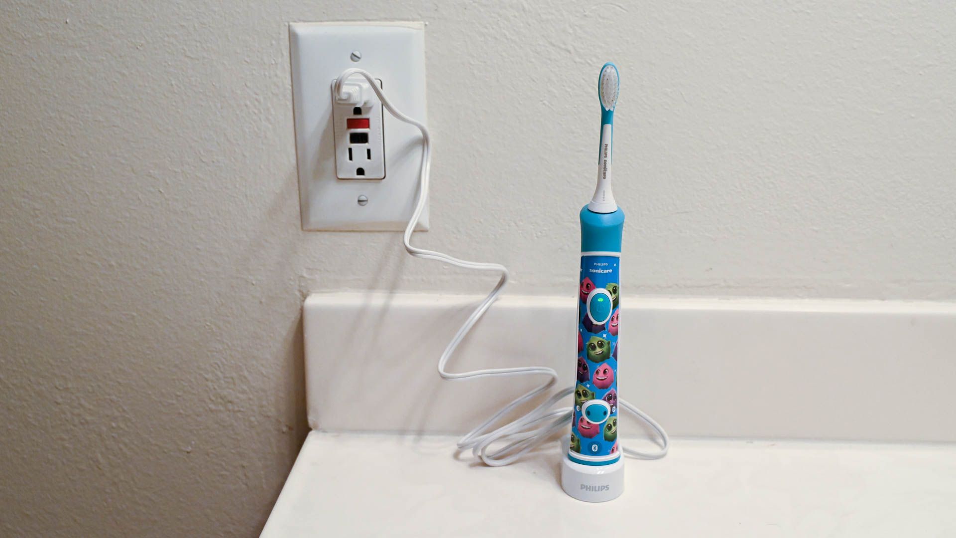An electric toothbrush plugged into the wall on a base
