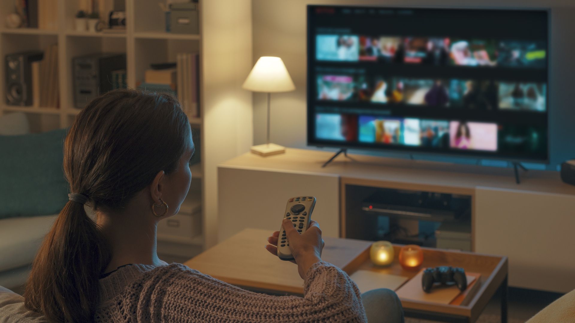 A woman relaxing on a couch browsing titles on a streaming service.