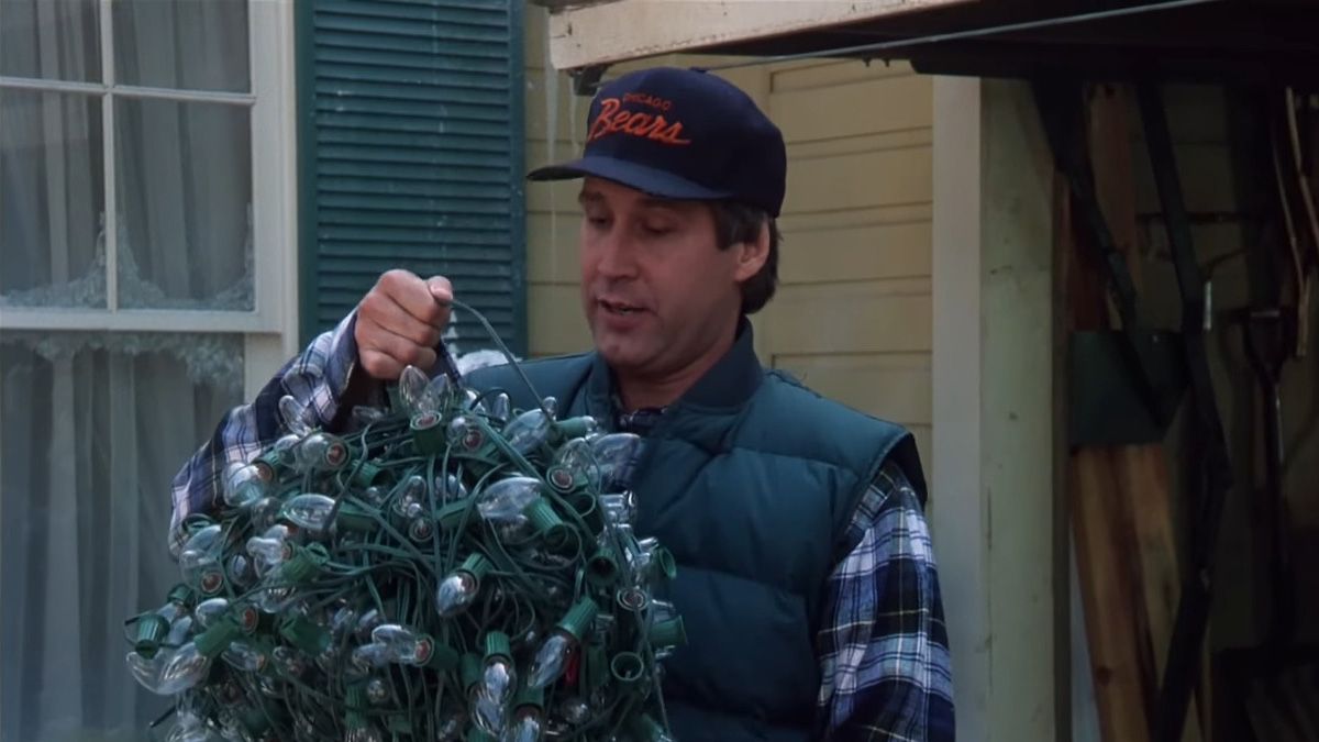 A man holds a ball of tangled up Christmas lights.