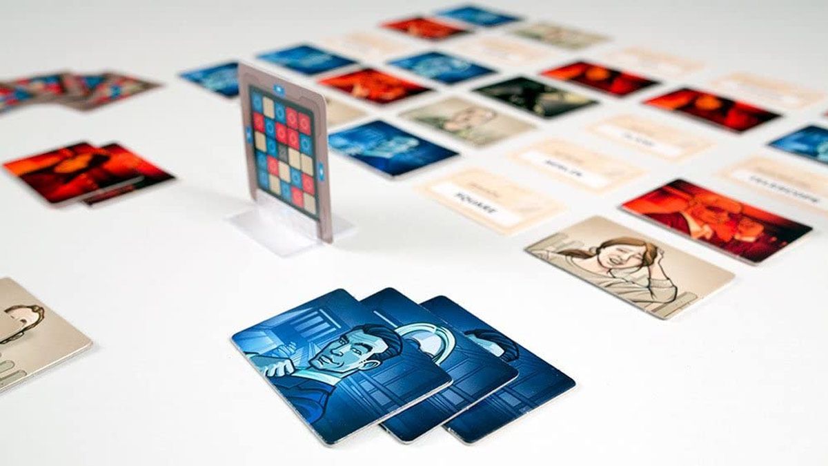 The tokens and cards for the game Codenames spread out on a table.