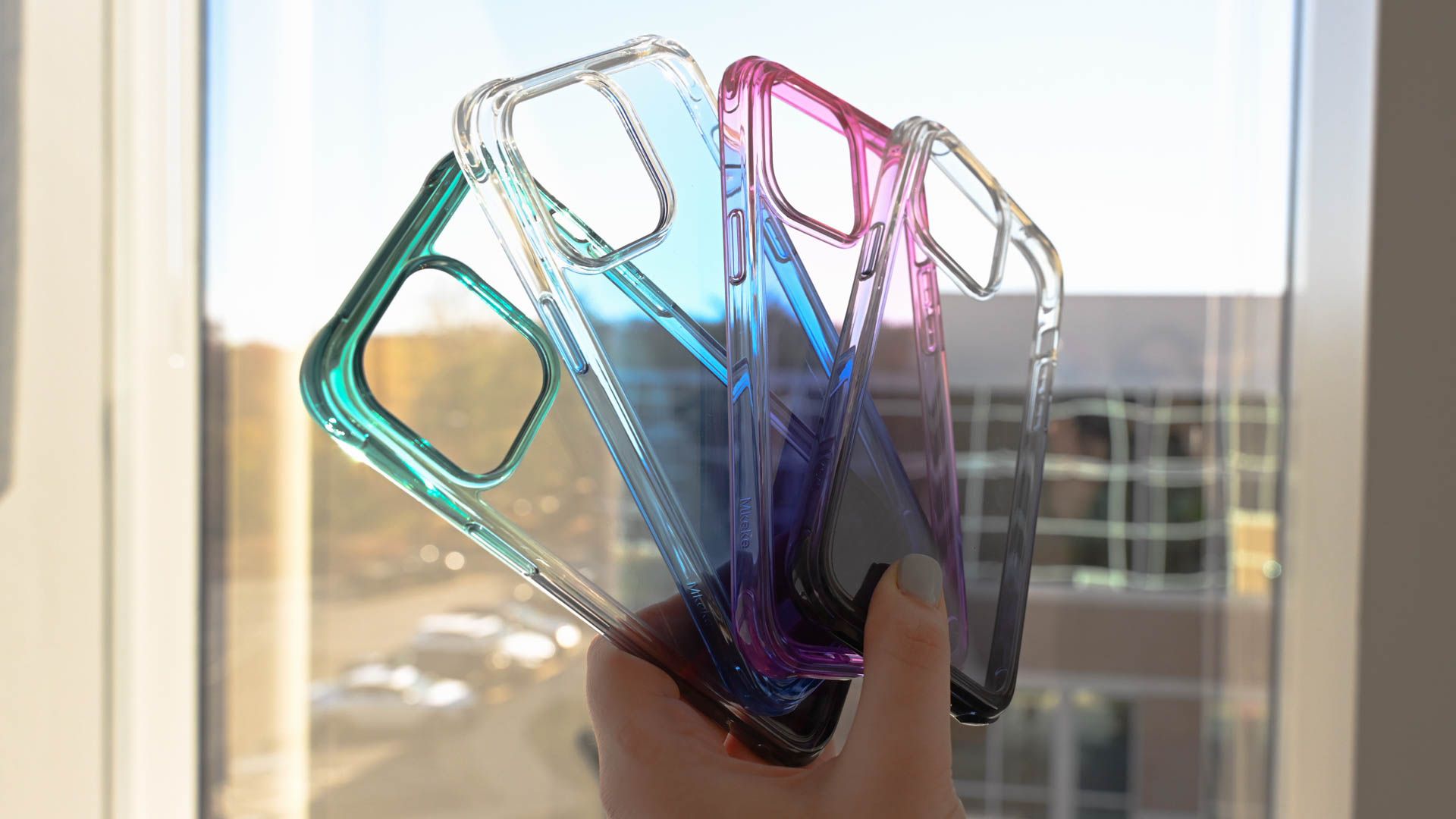 Person holding colorful Mkeke clear iPhone 14 Pro cases