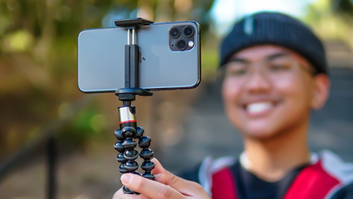 A young man holds a portable iPhone tripod.