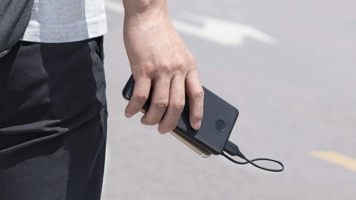 A person holds their phone and a portable battery pack.