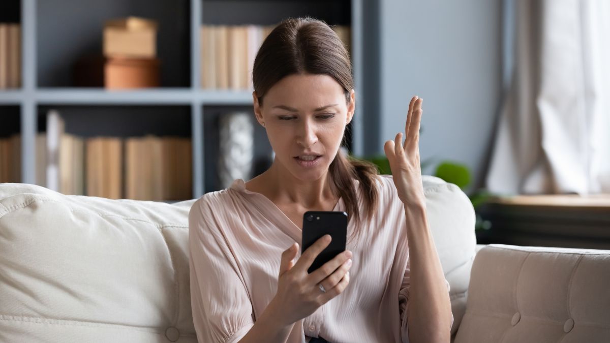 Woman looking at her phone with a confused or frustrated expression.