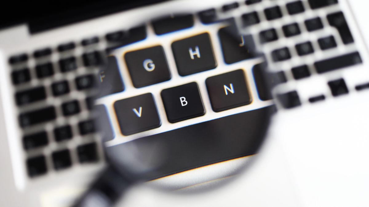 A magnifying glass held over a MacBook keyboard.