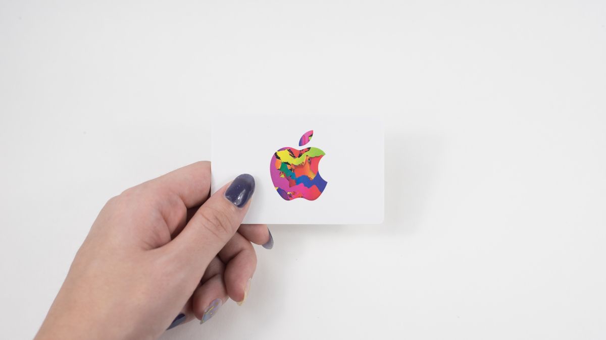Person's hand holding an Apple gift card against a white background.