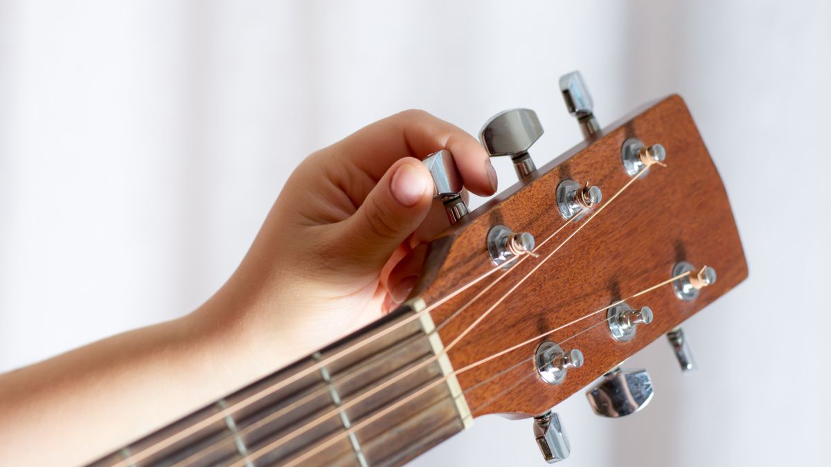 Person's hand tuning a guitar.