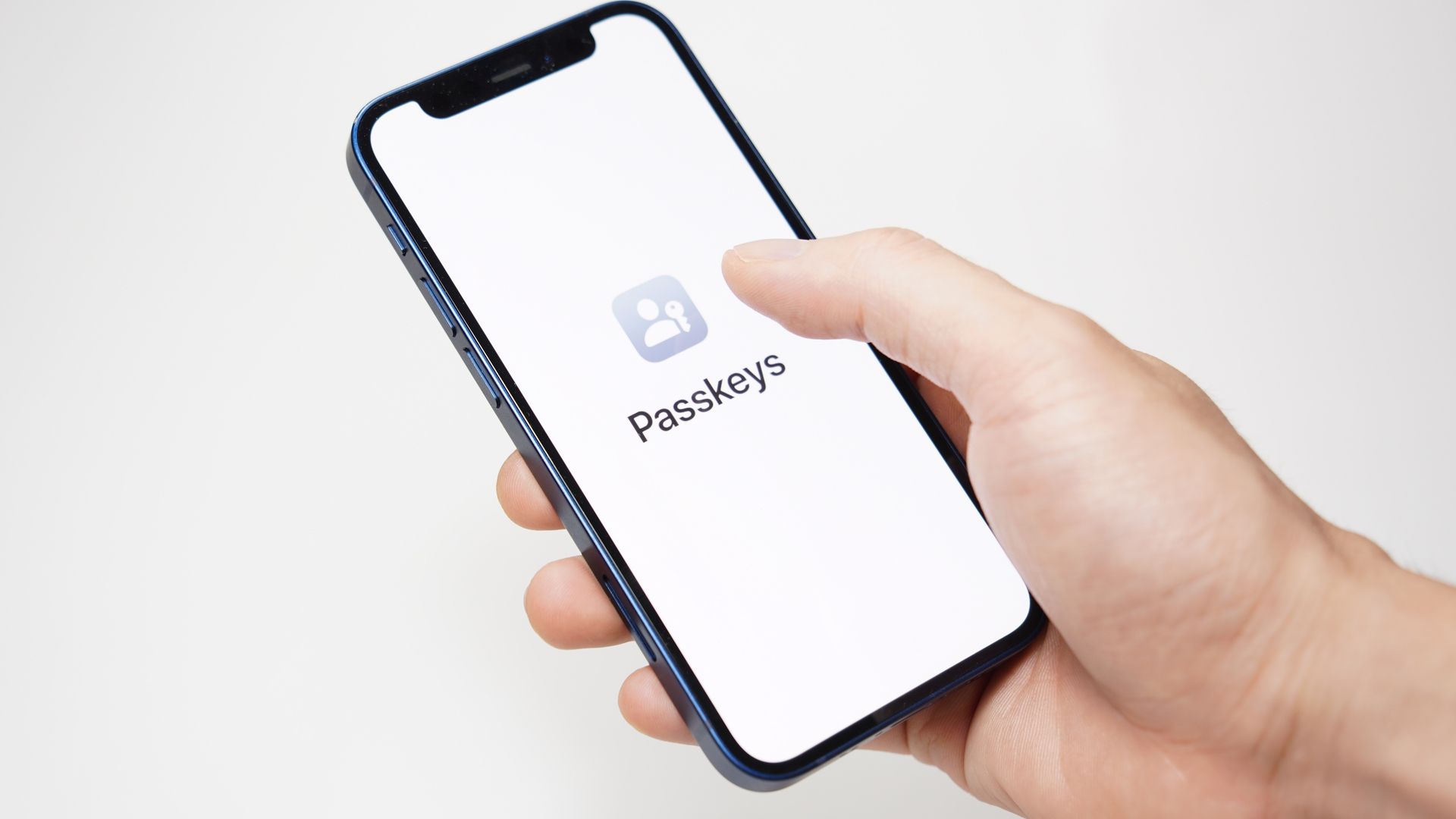 A hand holding a smartphone with the word &quot;passkeys&quot; on it.