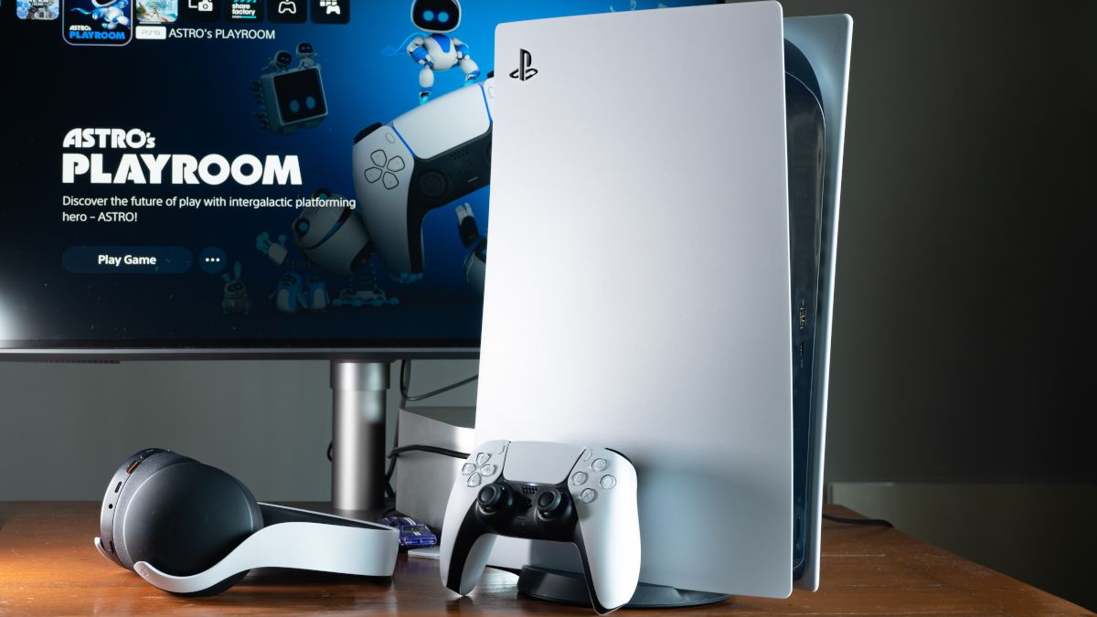 A Sony PlayStation 5 console on a desk with a controller, headphones, and monitor.