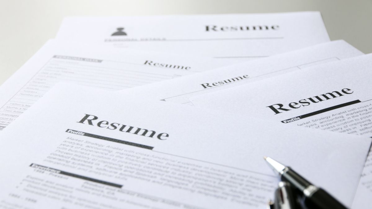 A collection of resumes scattered on a table.