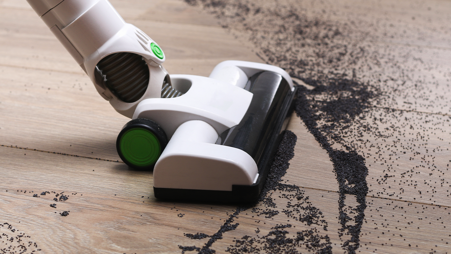 A cordless vacuum cleaning dirt off of hard floor.