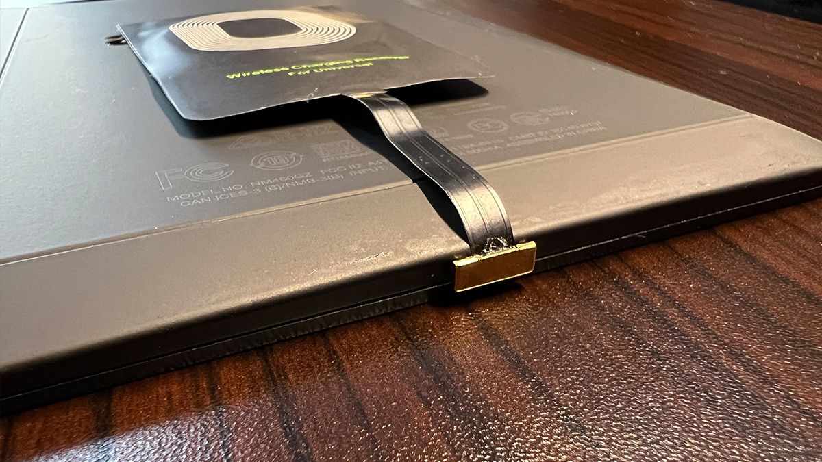 A wireless charging adapter fitted onto a Kindle eReader.
