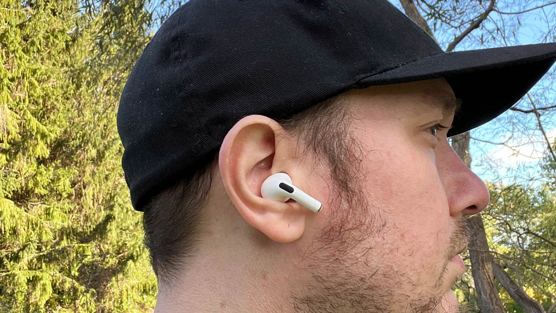 Wearing the 2nd generation AirPods Pro outside near a hedge.