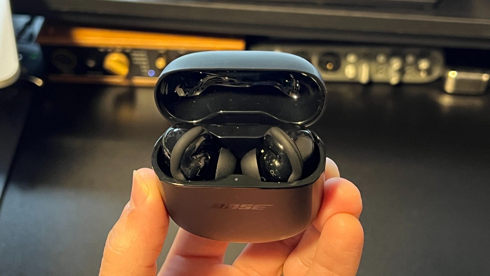 Bose Quiet Comfort 2 earbuds top in open case above black desk
