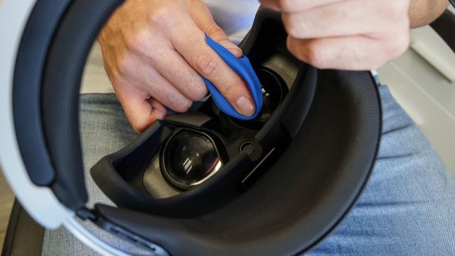 Closeup of a person's hands cleaning the lenses of a virtual reality headset.