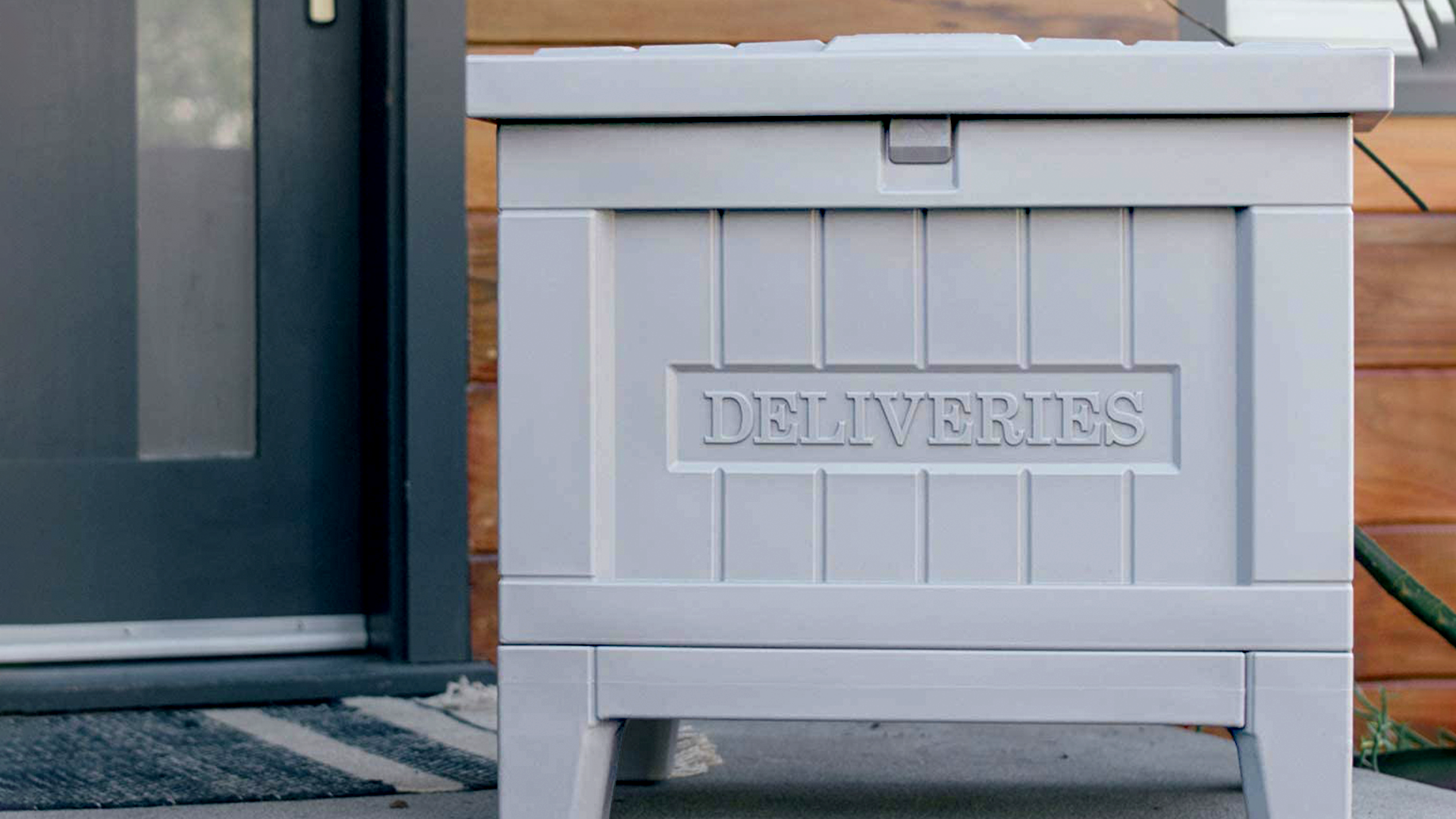 Yale Smart Delivery Box on a porch. It's a big gray plastic box.