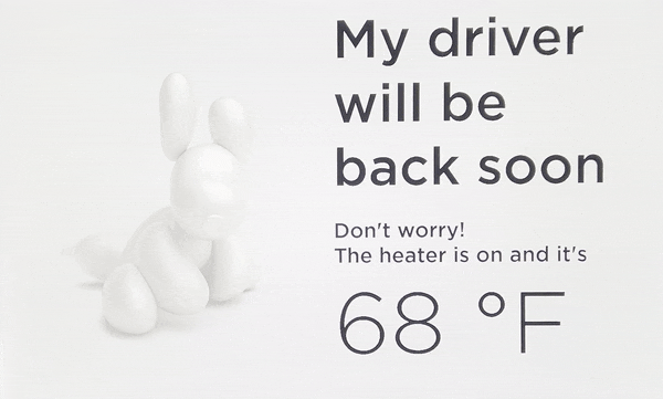 Screen displaying image of an animated dog wagging it's tail with the message "my driver will be back soon" and a temperature reading.