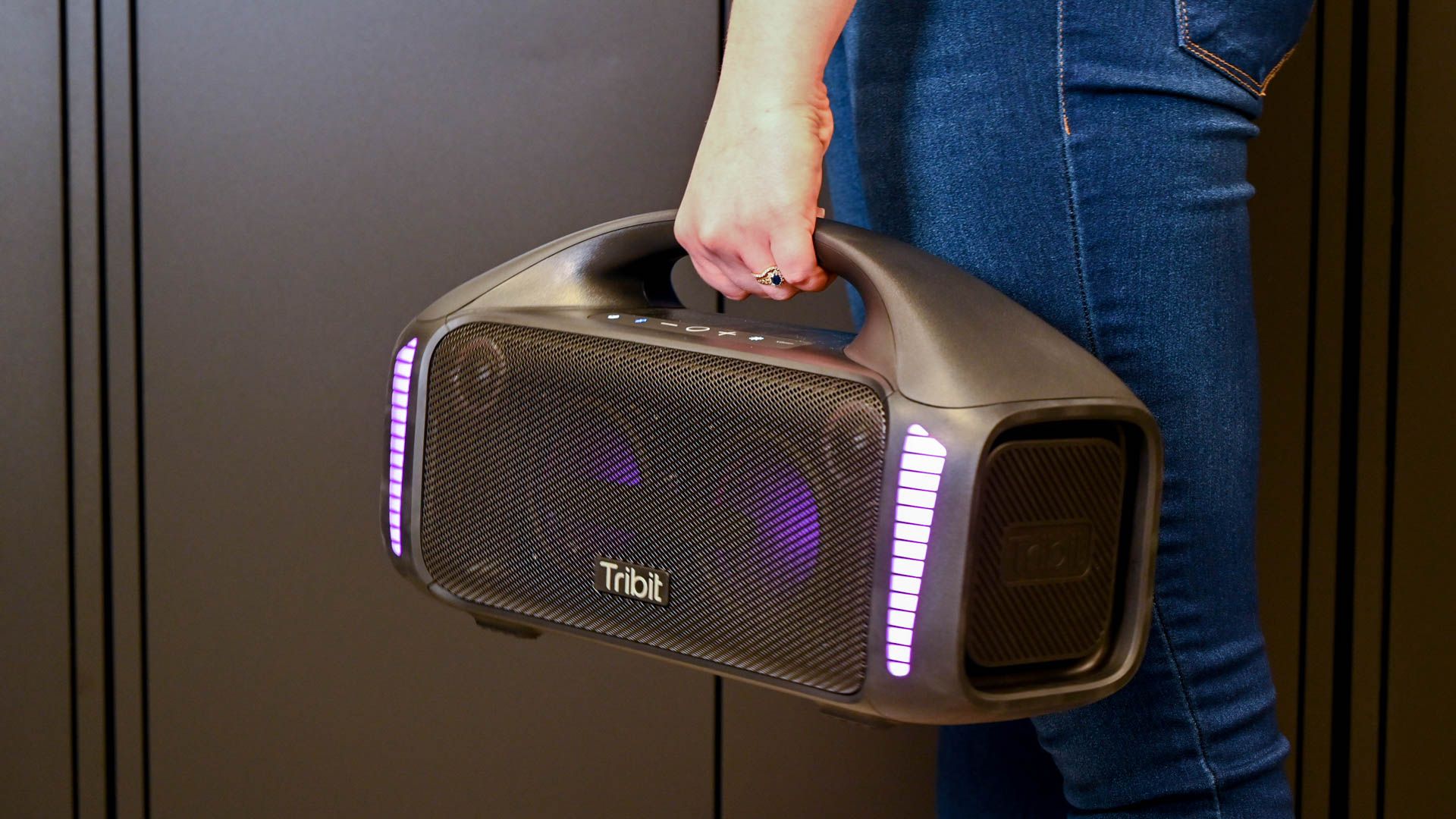 Person carrying the TriBit StormBox Blast Speaker with purple lights