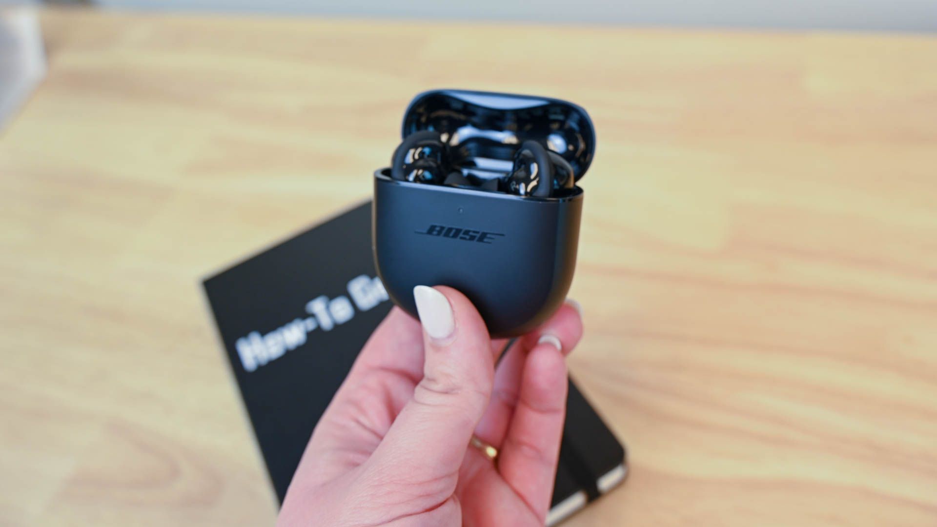 Person holding an open Bose QuietComfort Earbuds 2 case