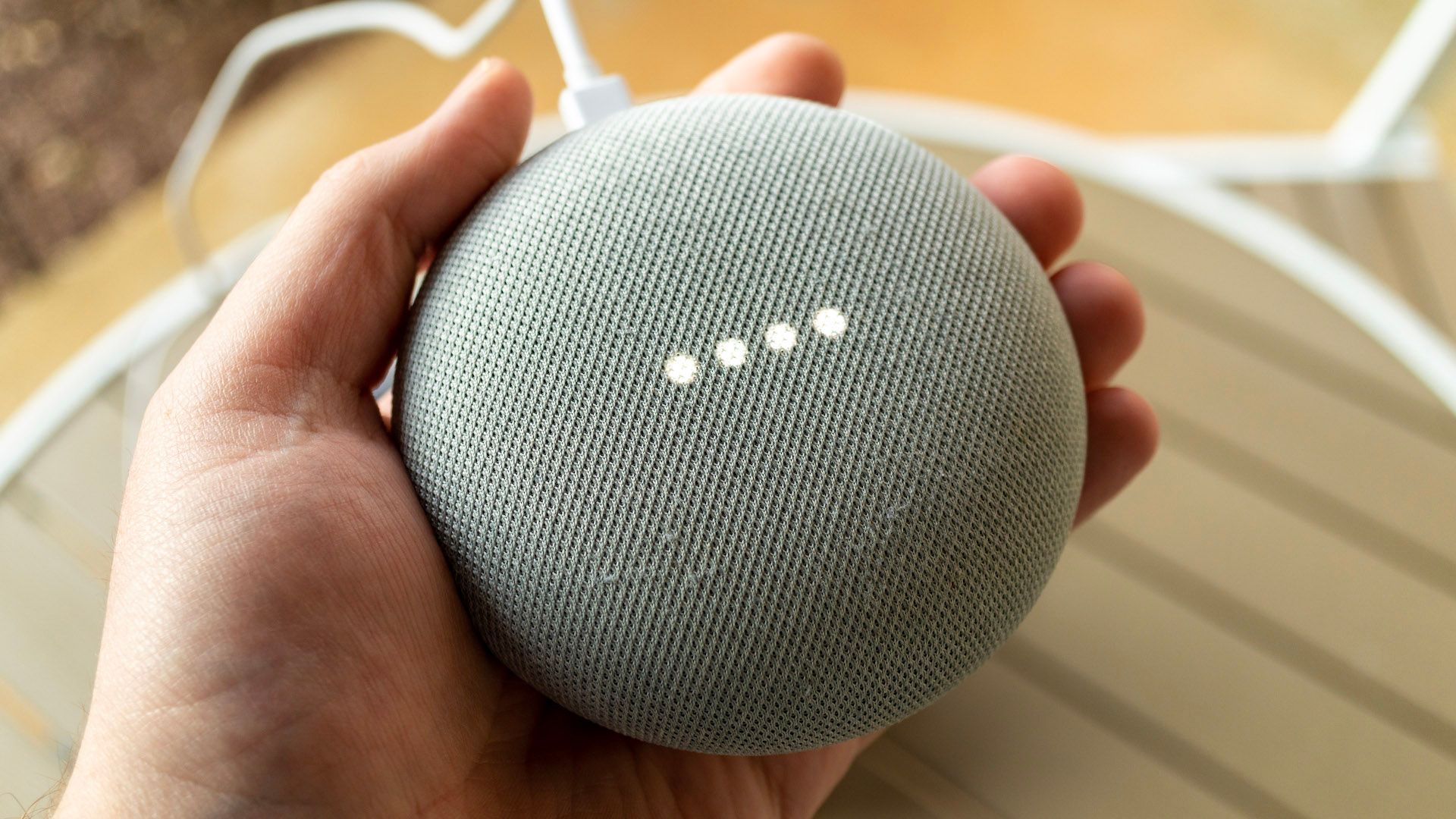 Person holding a Google Nest Mini smart speaker