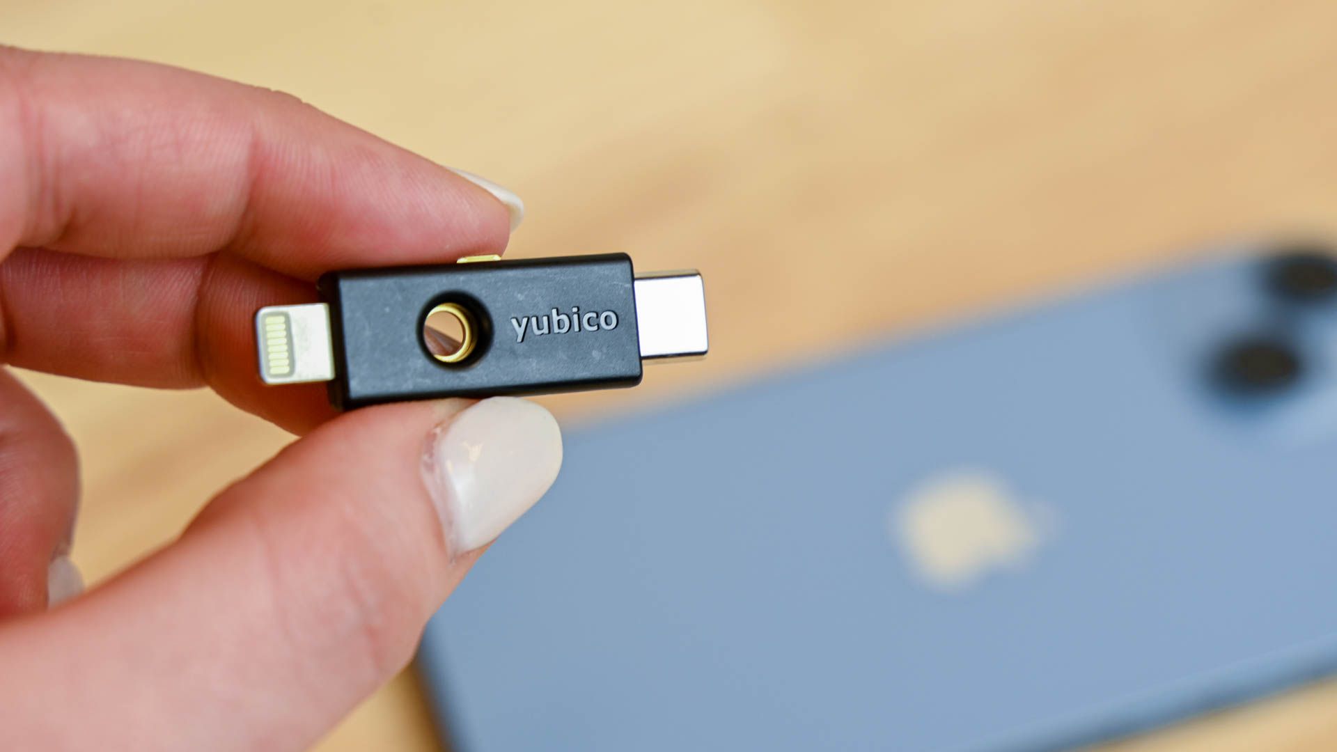 A person holding the Yubico Yubikey 5CI over an iPhone