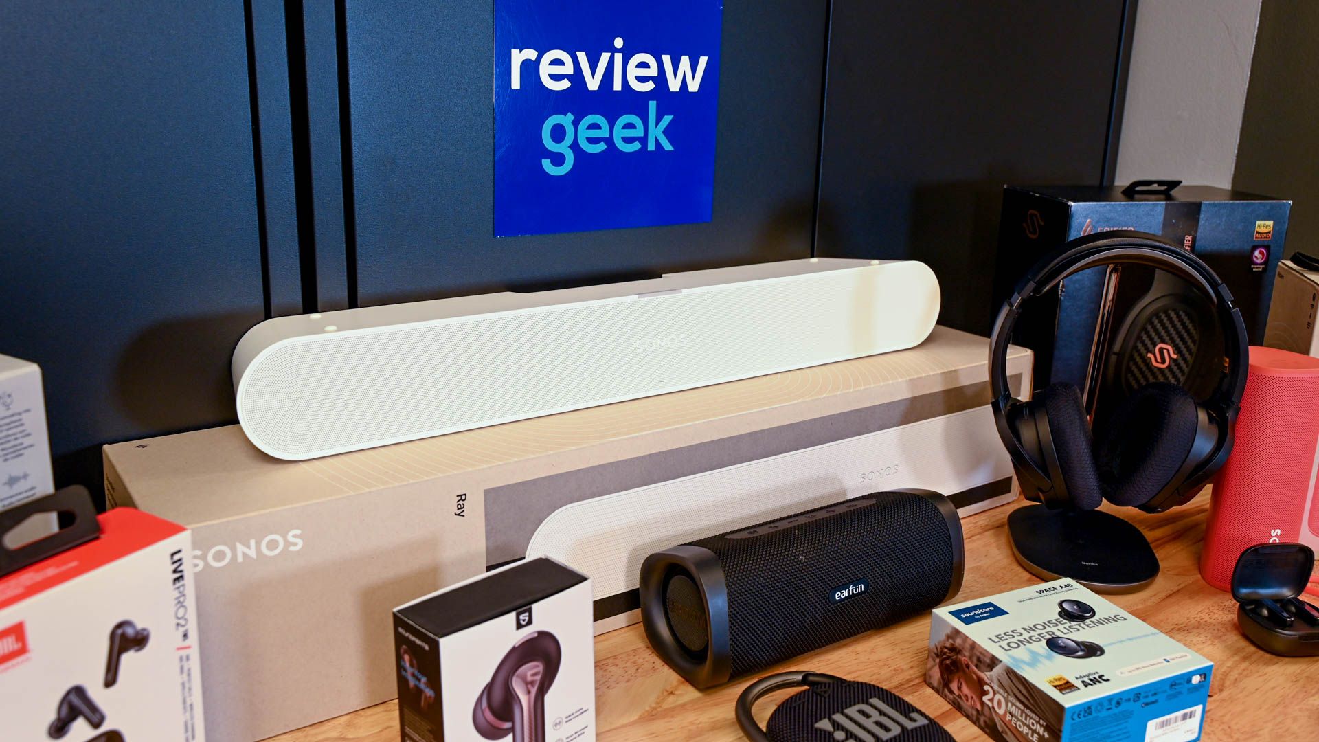 Collection of audio products, including soundbars and earbuds, with the Review Geek logo.