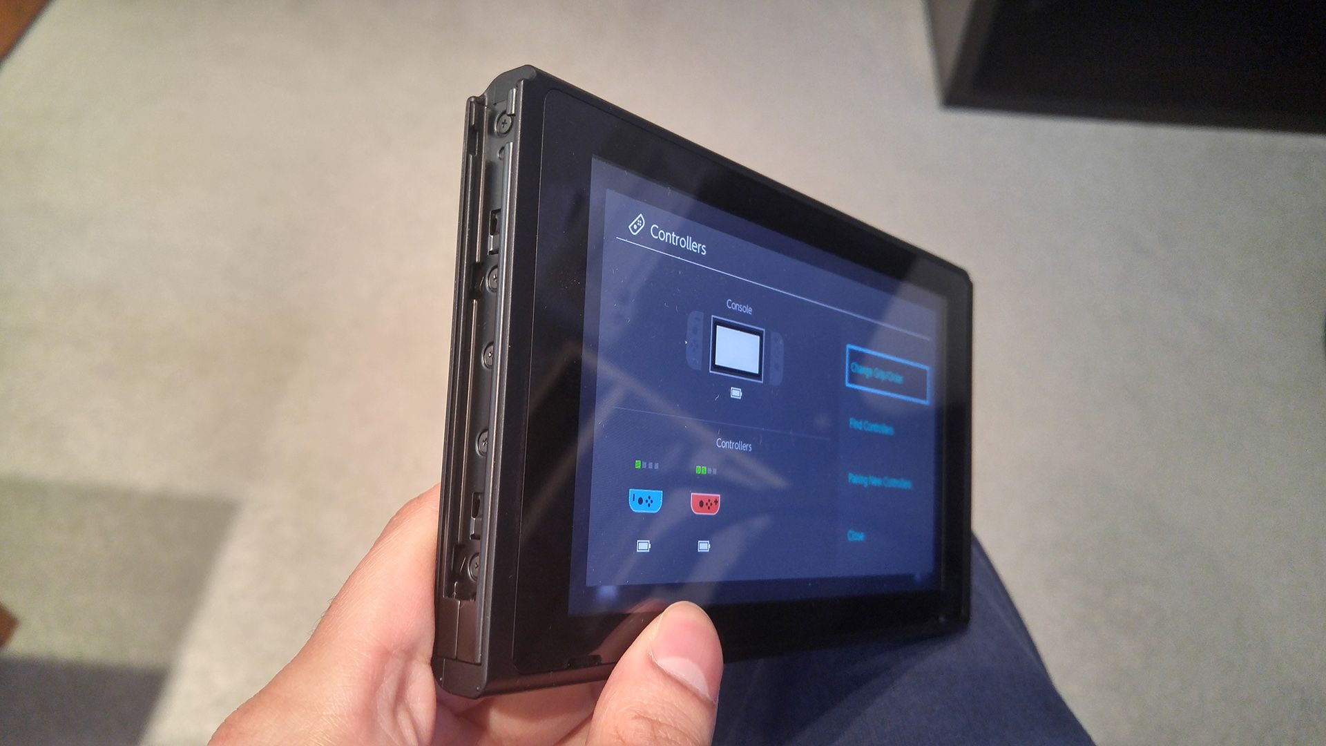 Holding a Nintendo Switch at an angle so that the left-side groove is visible.