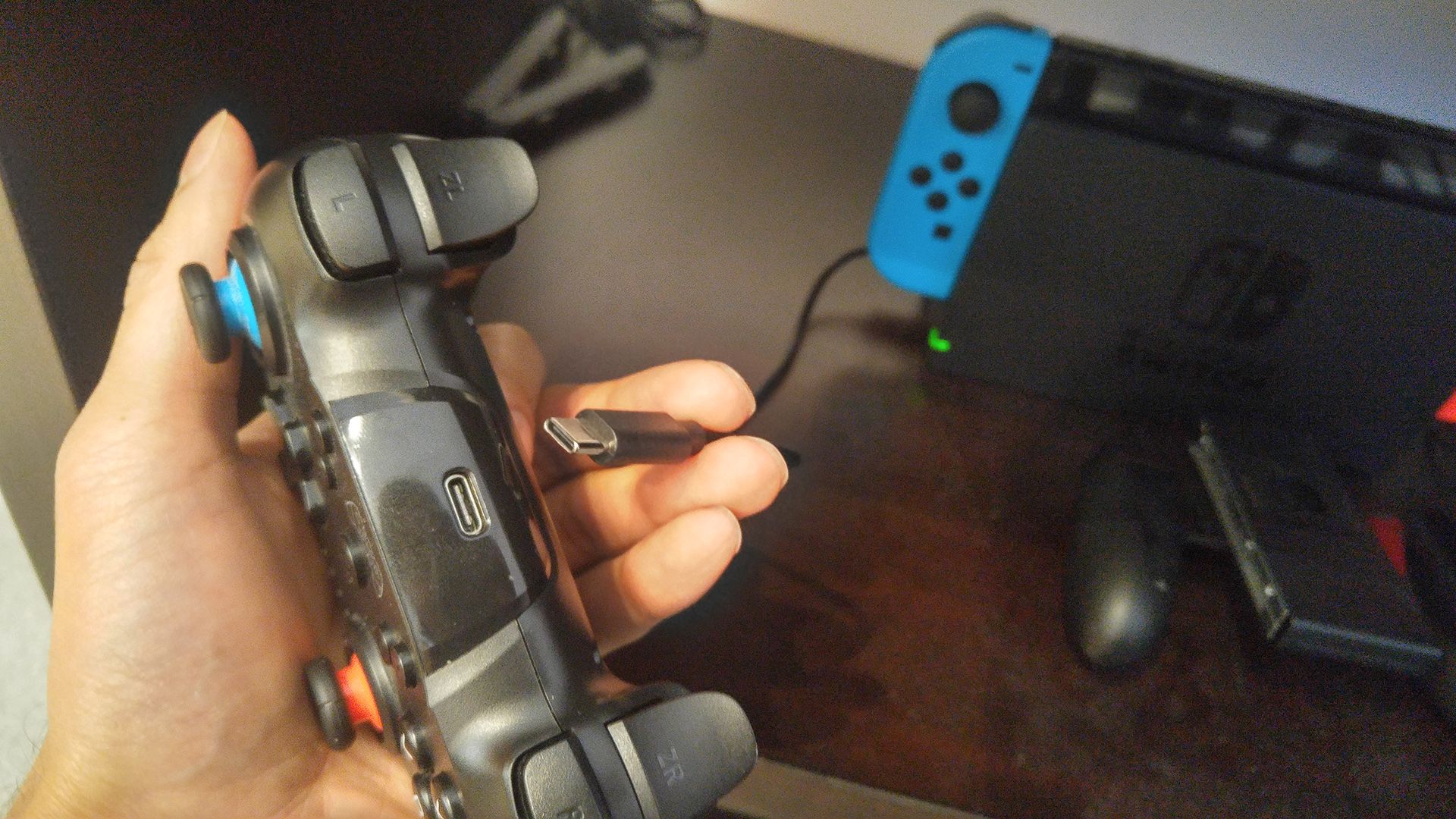 Holding a USB-C cable near the USB-C port of a Nintendo Switch controller.