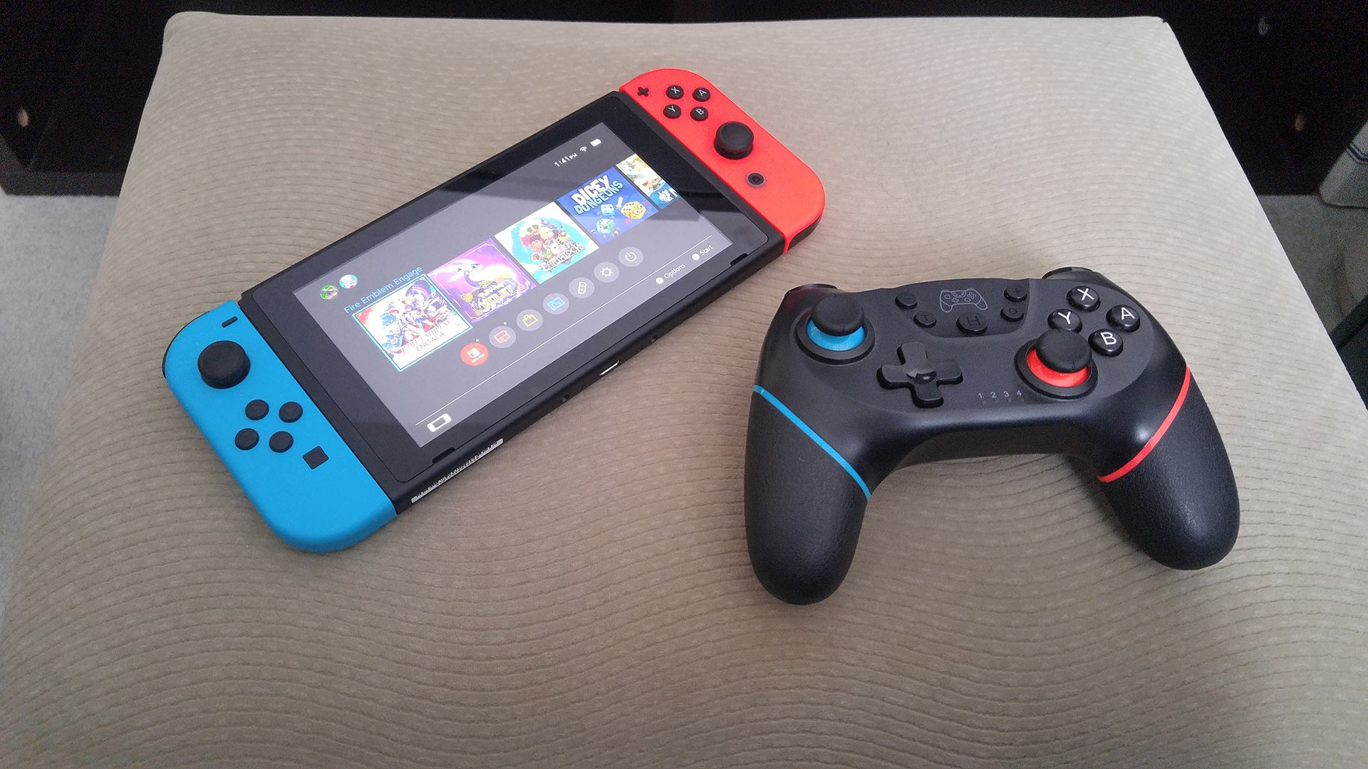 A Nintendo Switch tablet with Joy-Con controllers attached to it lying next to a Switch Pro Controller on a beige footrest.