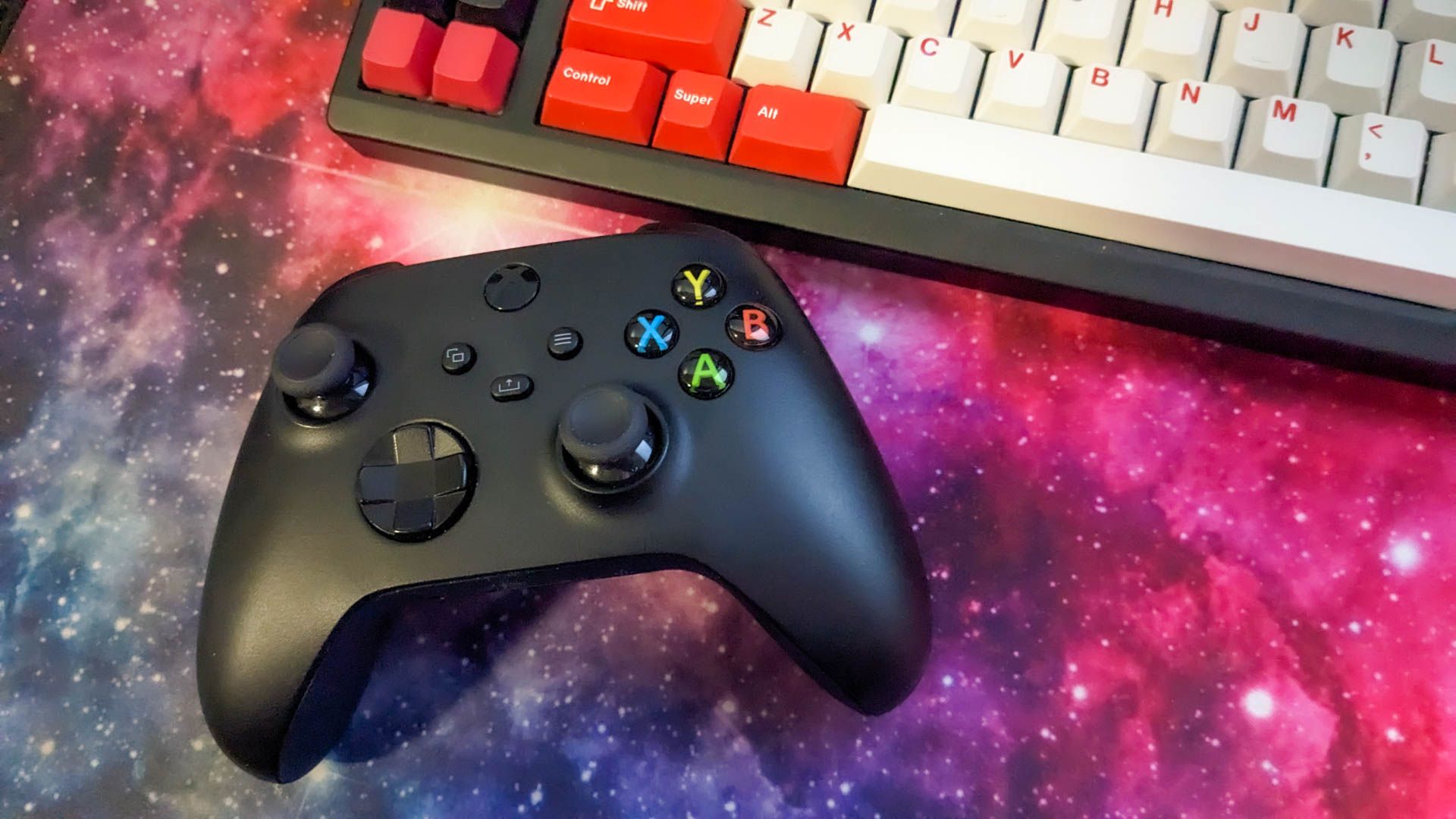 Xbox controller next to mechanical keyboard on space mousepad