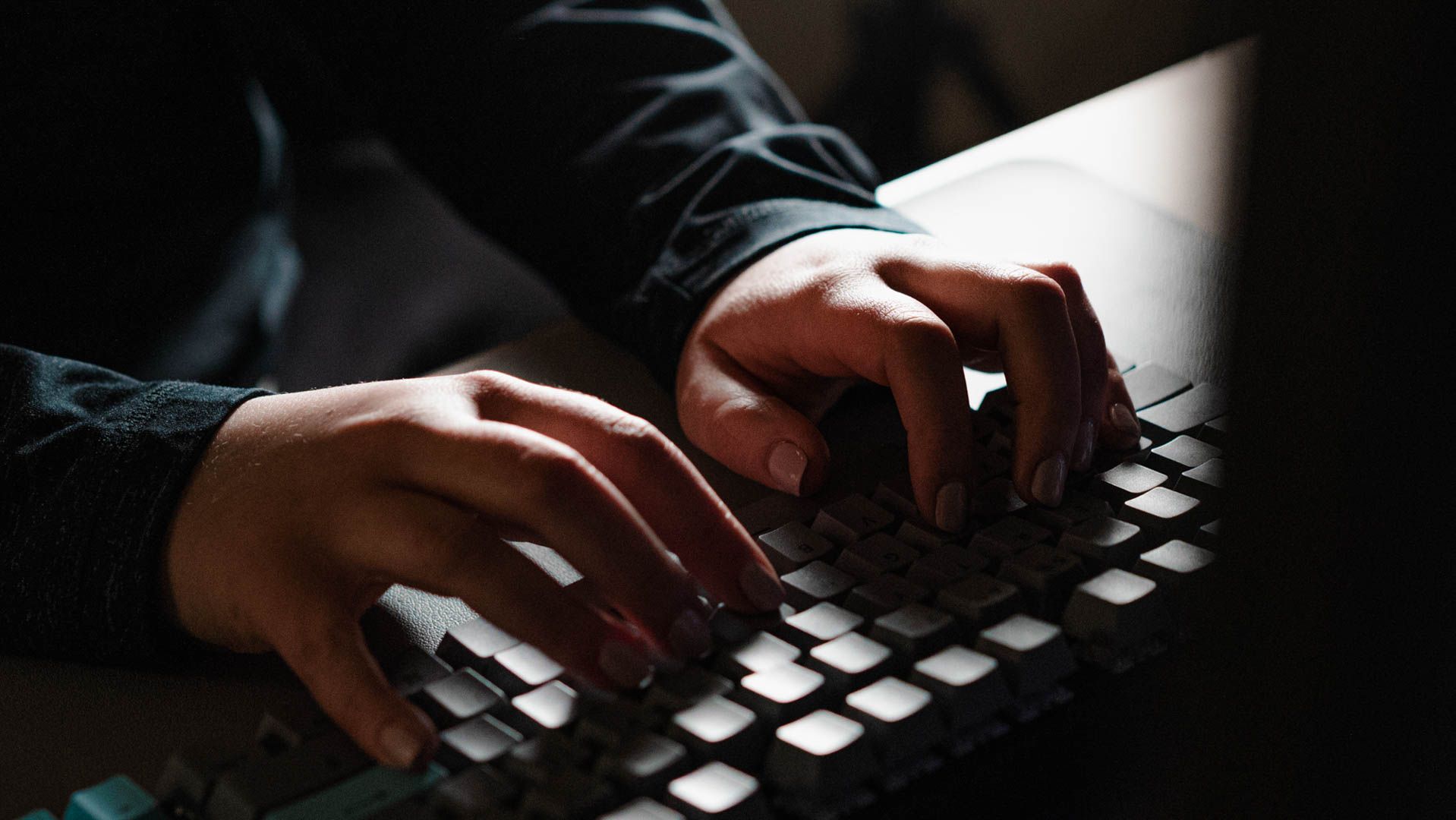 Person typing ominously on a dark keyboard